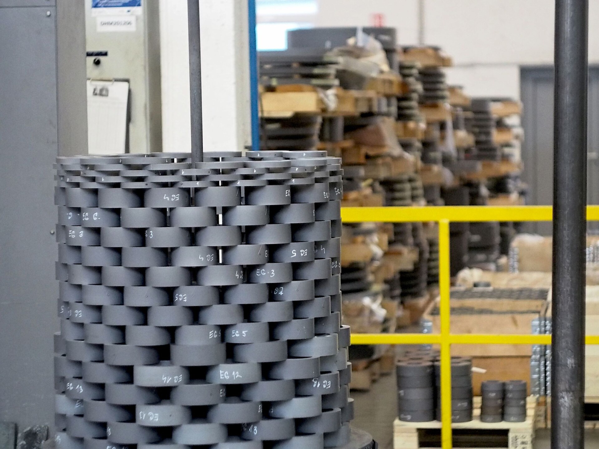 Stack of toroidal cores prepared for firing in a kiln, carefully suspended and ready for the calcination process. High material durability is crucial for transformers and other industrial applications.