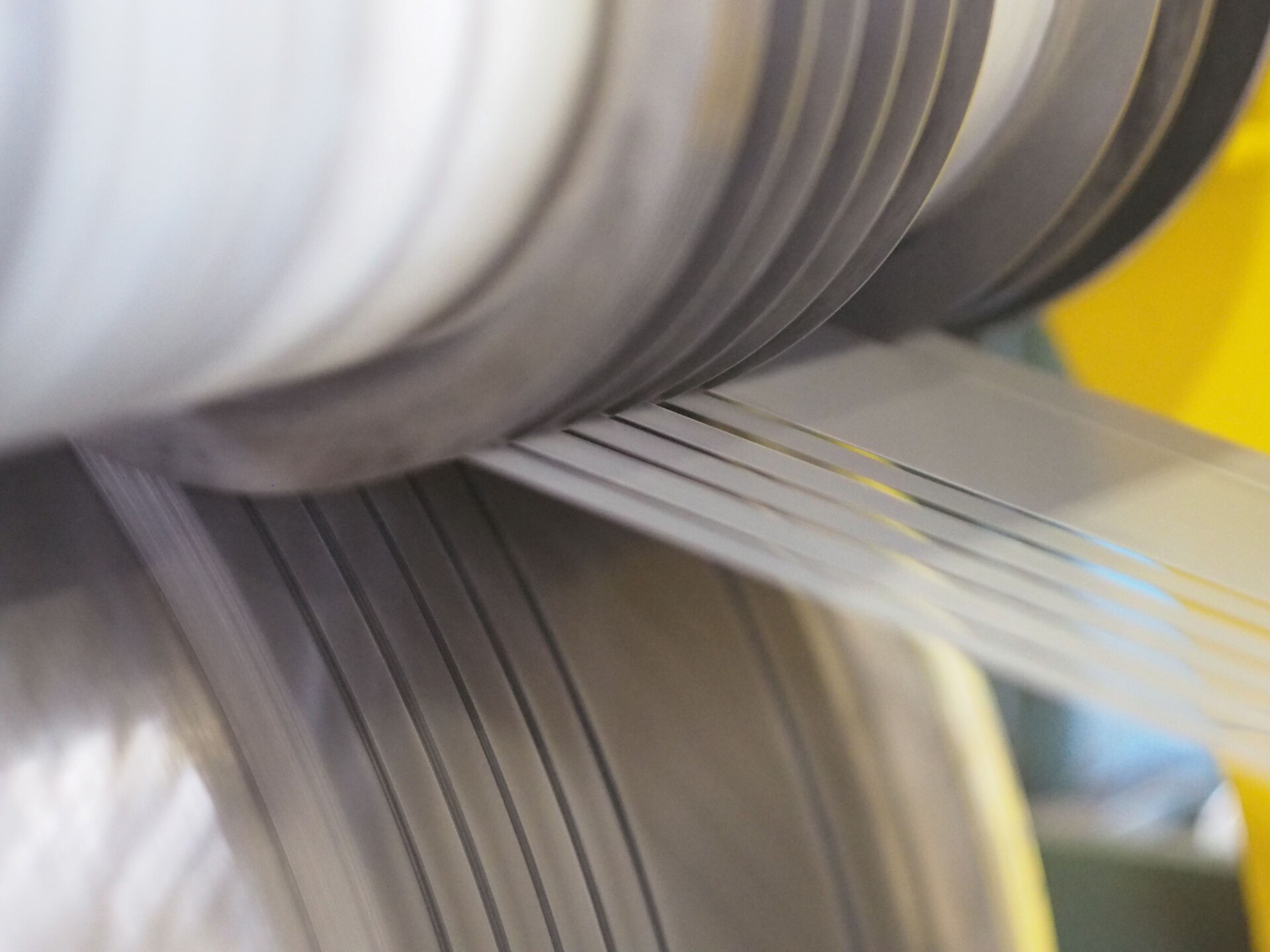 Close-up of a longitudinal slitting line in operation, showing precise cutting of metal sheets into narrow strips.